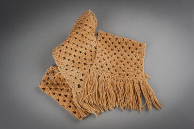 A khaki crocheted scarf with tassels at each edge