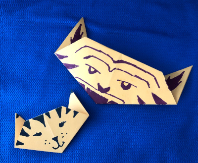 Two tiger heads made out of decorated yellow paper.